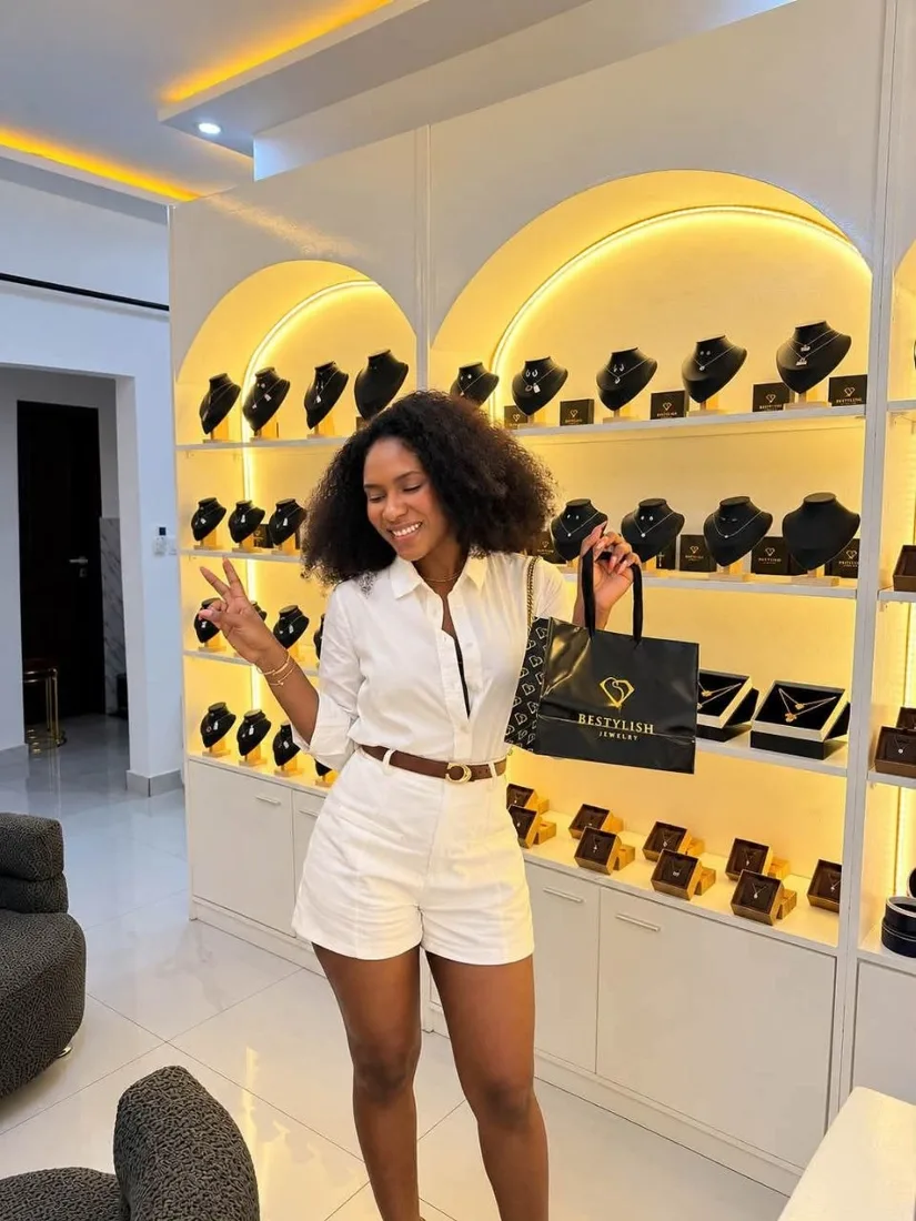 Une cliente souriante avec un sac Bestylish devant les vitrines du showroom